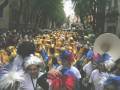 Una multitud de personas con disfraces coloridos y plumas, participando en un desfile festivo.