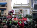 Desfile de carros alegóricos en una celebración con personajes de fantasía en el centro de una calle animada.