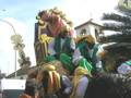 Desfile de Reyes Magos en una ciudad española. Personas vestidas con trajes tradicionales y un carro adornado participan en la celebración.
