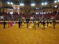 Un grupo de toreros camina por el ruedo durante una corrida de toros en un anfiteatro histórico lleno de espectadores.