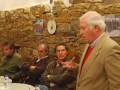 Un hombre habla en una reunión informal en un ambiente rústico con paredes de piedra.