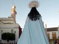 Procesión de la Virgen con manto azul en una plaza histórica.