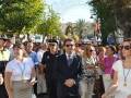 Una multitud en una procesión religiosa, con personas vestidas formalmente y un hombre con sombrero de policía. El ambiente es solemnemente festivo, con árboles y edificios al fondo.