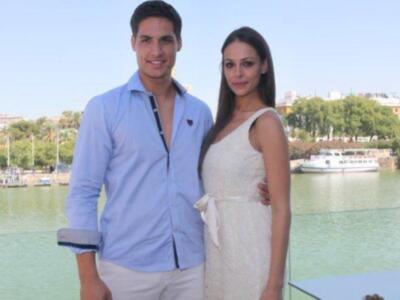 Dos personas posando junto a un río con un barco en el fondo, en un ambiente soleado y relajado. La escena sugiere una ocasión especial o formal en un entorno natural.