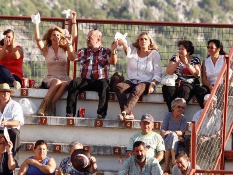 Asistentes animando en una tribuna al aire libre.