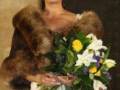 Una mujer con un vestido blanco y una capa de piel marrón, sonriendo mientras sostiene un ramo de flores multicolores.
