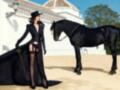 Elegancia negra: una mujer con vestido largo y sombrero negro posa junto a un caballo negro en un entorno rural.