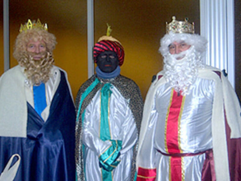 Tres personajes vestidos como los Reyes Magos, con túnicas y coronas, posando juntos.