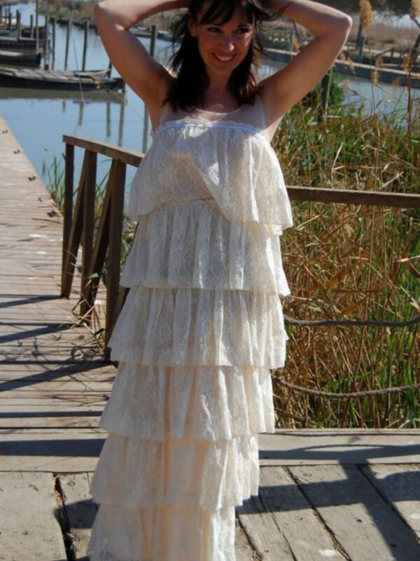 Mujer con vestido blanco de encaje en un muelle junto a un río.