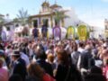 Fiesta en Sevilla, España. Personas celebrando con carros alegóricos y banderas ondeando en el fondo.