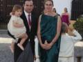 Una familia elegante en un evento formal, con una mujer en un vestido verde y un hombre en traje negro.