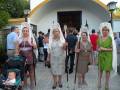 Una familia vestida con trajes tradicionales de la región, posando frente a una pequeña iglesia. La imagen muestra detalles como sombreros blancos y vestidos coloridos, con un bebé en una silla de paseo a la izquierda.