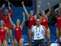 Equipo español de waterpolo celebrando victoria con el entrenador en el banquillo.