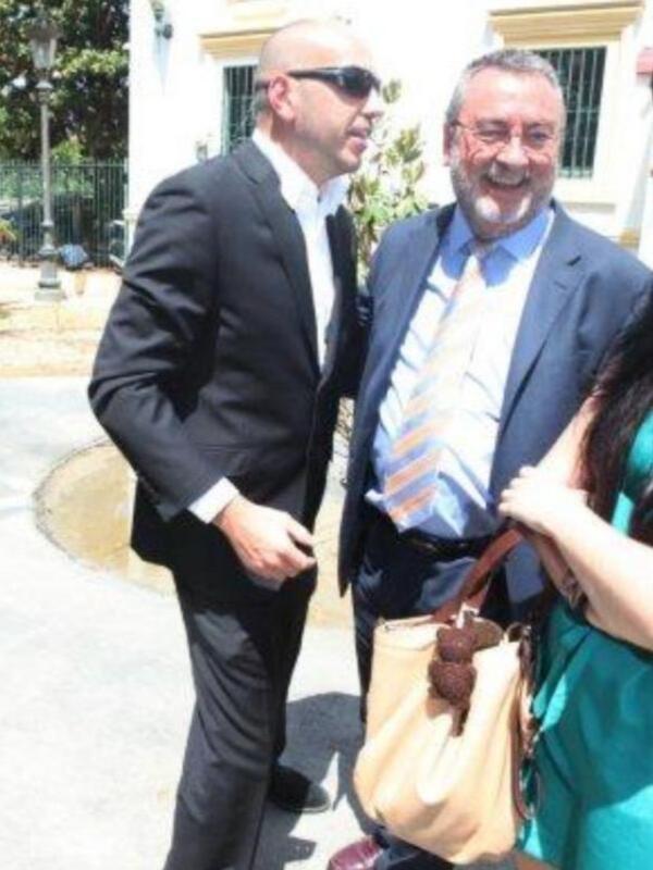Dos hombres en traje sonrientes y conversando al aire libre.