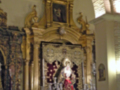 Altar con estatua central, candelabros y adornos religiosos.