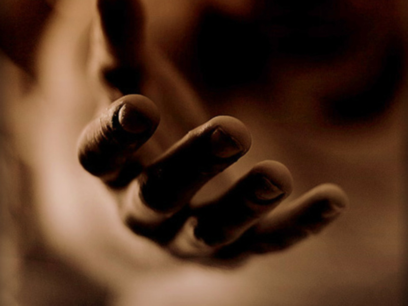 Mano con dedos extendidos, fondo borroso. Tono sepia.