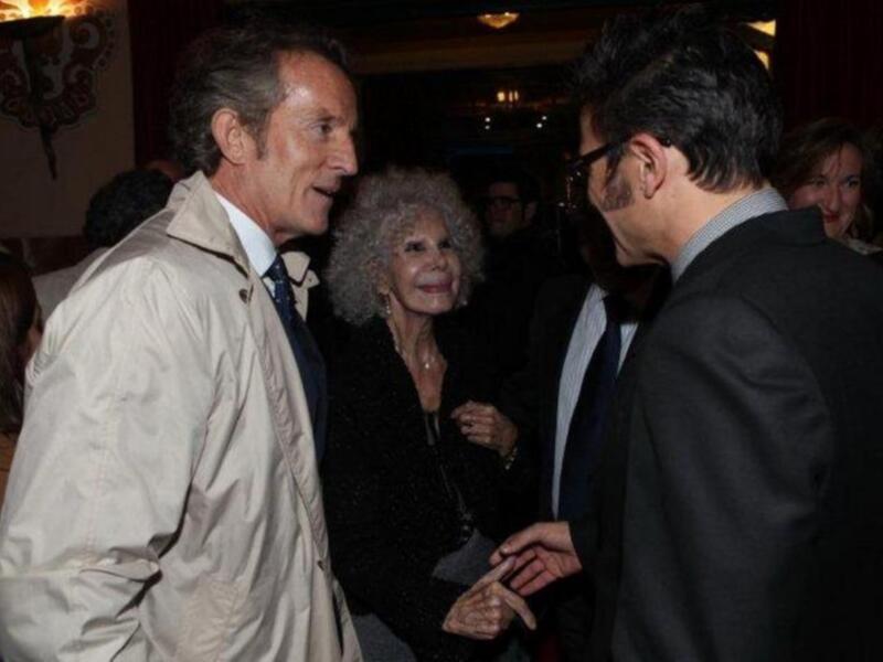 Persona mayor intercambiando saludos con otros en un evento social.