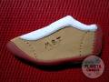 Galleta en forma de zapatilla con el logo "MBT" en el talón, sobre fondo rojo.