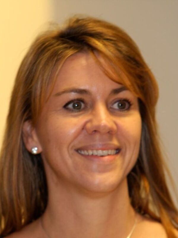 Una mujer con cabello largo y ondulado, sonriendo. La imagen parece estar tomada en un evento formal o profesional.