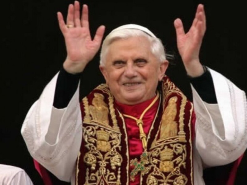 El Papa Benedicto XVI, con sus manos levantadas en un gesto de saludo.