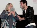 Celebración de un premio en un evento público, con una mujer recibiendo un galardón de manos de un hombre sonrientes.