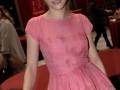 Una mujer con vestido rosa y cabello recogido, posando en un evento.