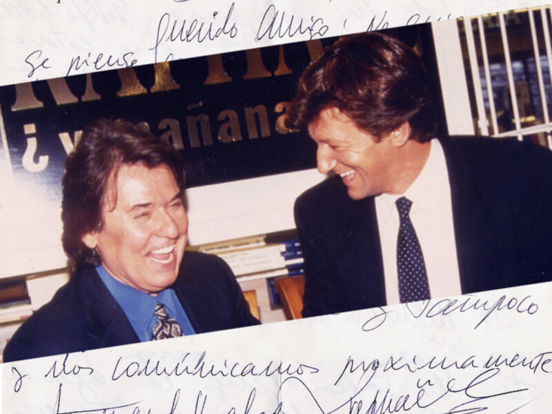 Dos hombres sonrientes en una foto de 2001. La imagen está firmada por ambos y contiene un mensaje en español.