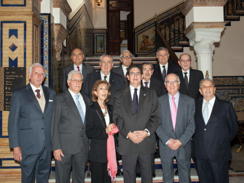 Grupo de personas posando para una foto en un entorno decorado con azulejos y columnas, posiblemente en un edificio histórico o institucional.