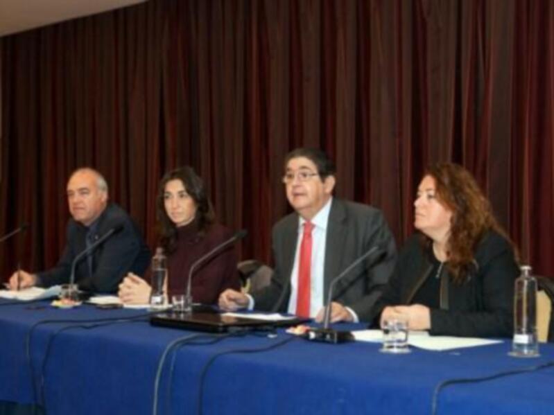 Conferencia de prensa con cuatro participantes sentados detrás de un mostrador con micrófonos y documentos.