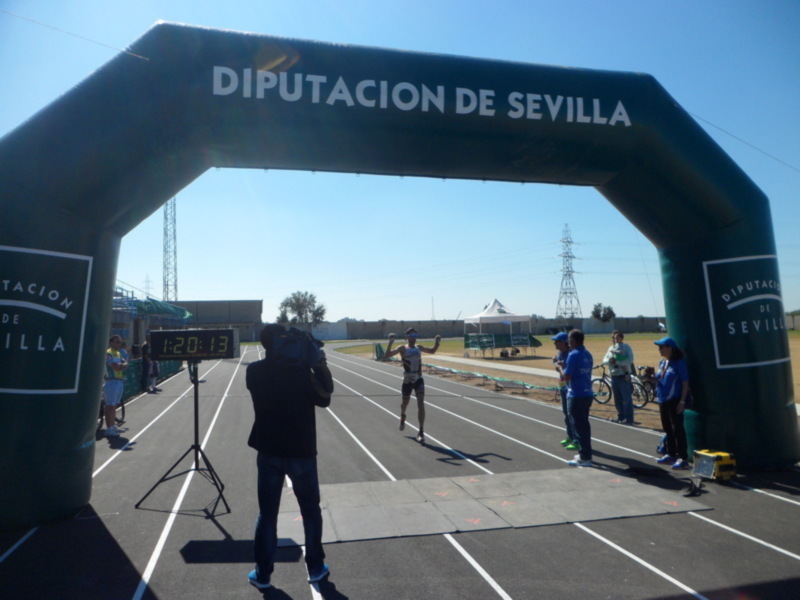 Atleta cruzando la meta en una carrera de atletismo en Sevilla.