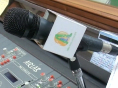 Un micrófono profesional con un logo de radio en el fondo, mostrando una estación de radio.