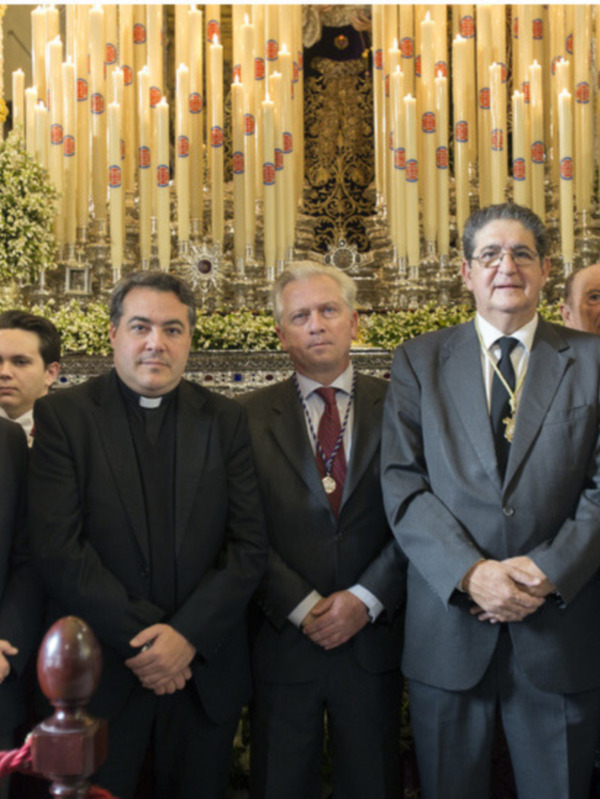 Oficiales y autoridades posan para una foto en una ceremonia religiosa dentro de una iglesia decorada con velas y flores.