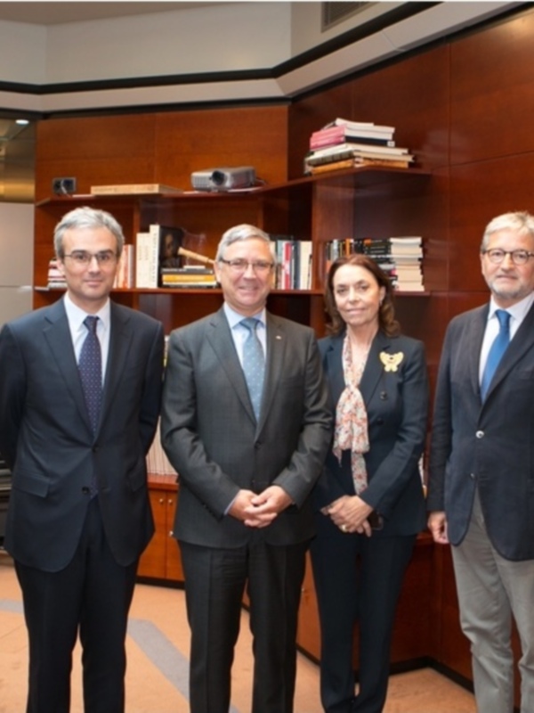 Reunión de autoridades en un ambiente formal con libros y tecnología en el fondo.