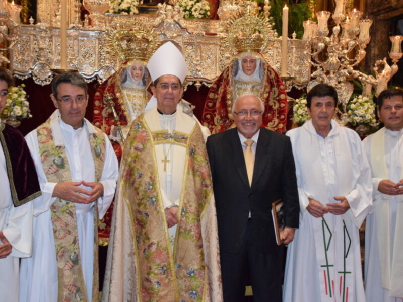 Celebración religiosa con sacerdotes y autoridades en un entorno ornamental y festivo.