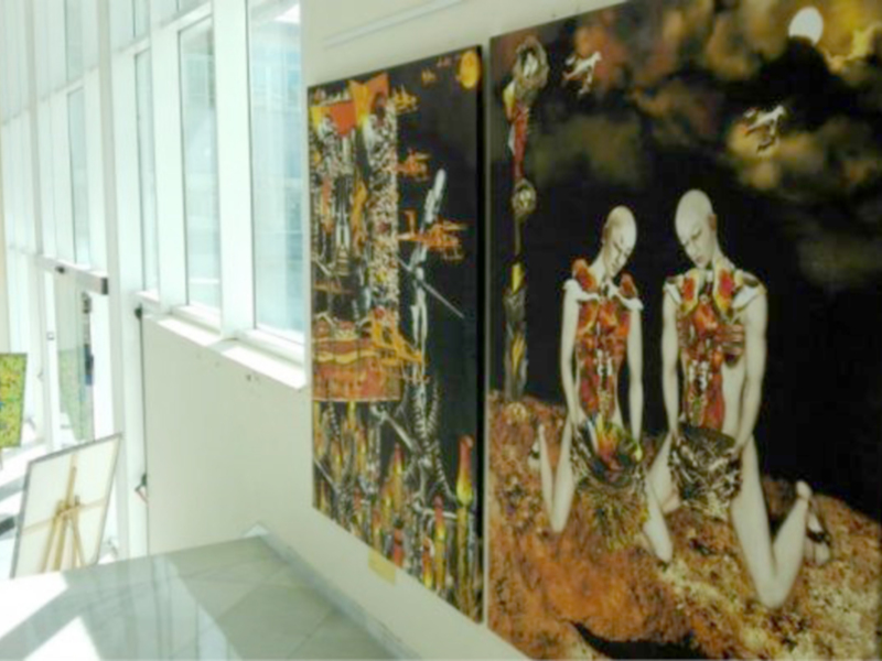 Dos cuadros de arte moderno colgados en una pared con ventanas a la izquierda. Los cuadros muestran figuras femeninas en diferentes posturas y colores vibrantes. La imagen tiene un ambiente de arte contemporáneo y creativo.