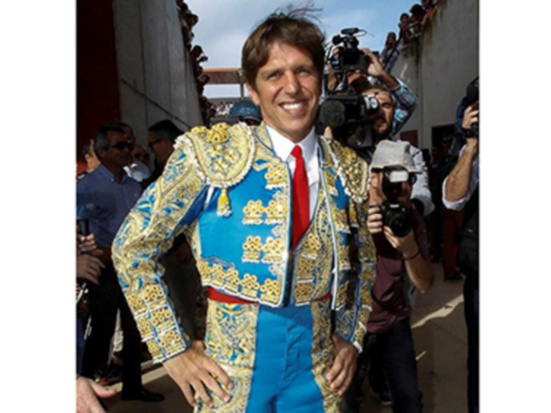 Matador in traditional costume posing amidst photographers during a public event.