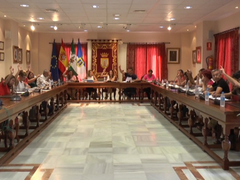 Sala de reuniones con mesa central, sillas alrededor y banderas en el fondo.