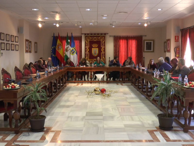 Reunión de trabajo en una sala de conferencias con banderas y escudos de España y Andalucía.