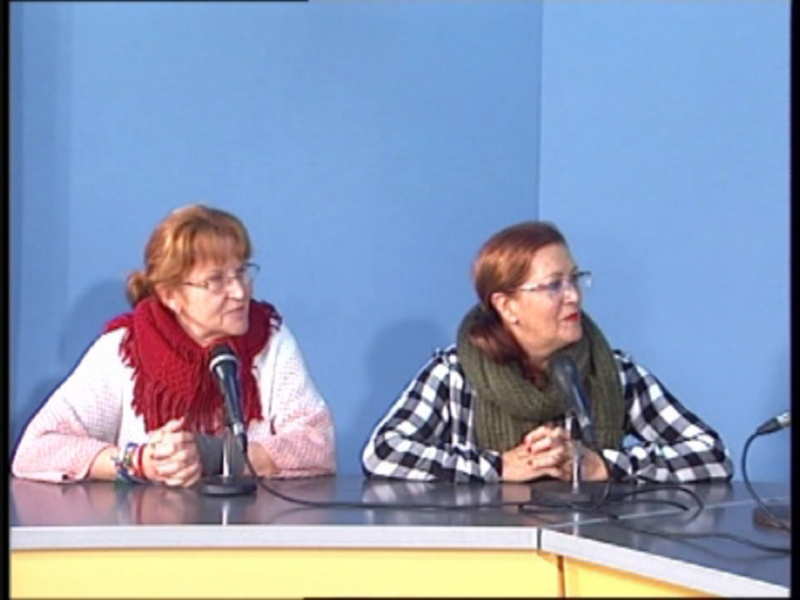 Dos mujeres sentadas detrás de un mostrador con micrófonos, posiblemente en una entrevista o conferencia.
