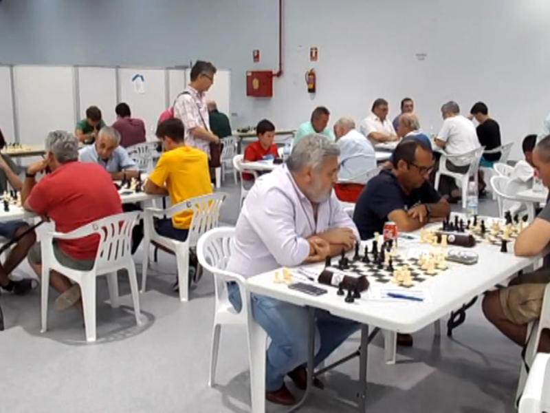 Jugadores de ajedrez en un torneo, sentados a mesas con tableros de ajedrez.