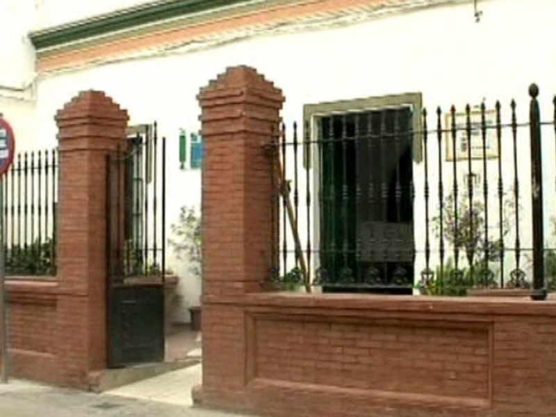 Puerta de acceso a una casa con muralla de ladrillos y valla metálica en la entrada.
