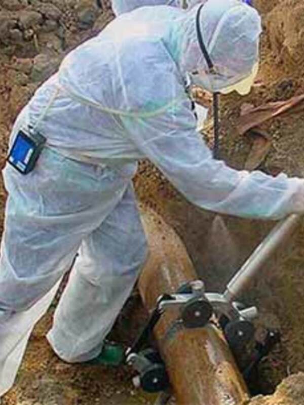 Un trabajador en traje de protección está perforando un agujero en el suelo con una máquina de perforación.