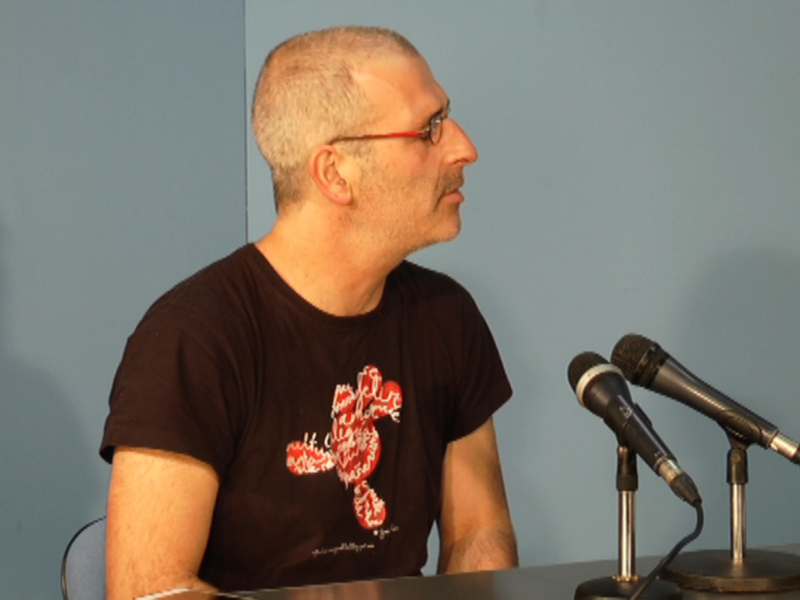 Persona hablando en un evento con microfonos en primer plano.