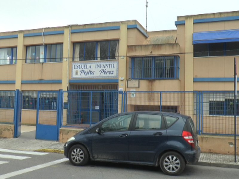Escuela Infantil Pedro Pérez, edificio de color beige con azulejos azules. Parking con una pequeña camioneta negra.