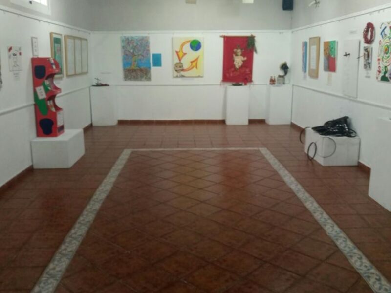 Salón de exposición con diversos murales y arte en las paredes, mostrando una variedad de estilos y colores.
