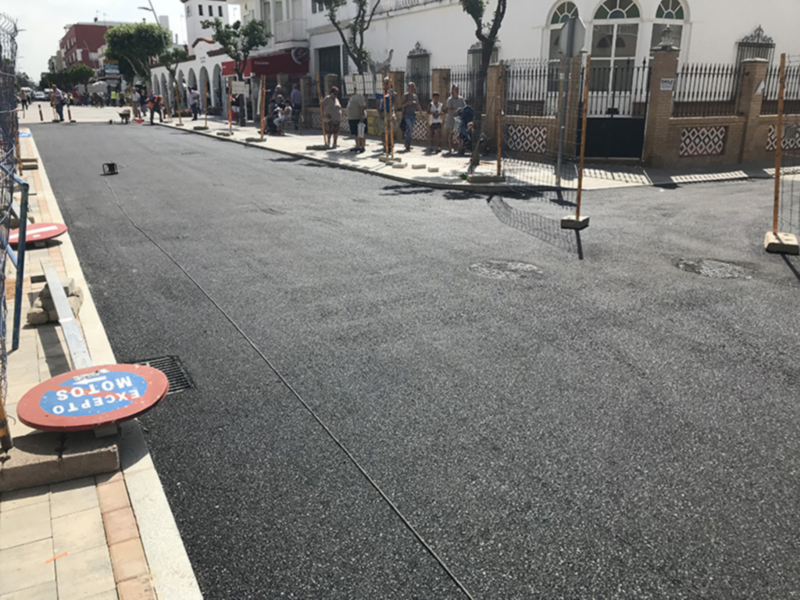 Piso de hormigón recién asfaltado en una calle con señales de tráfico y un parque infantil.