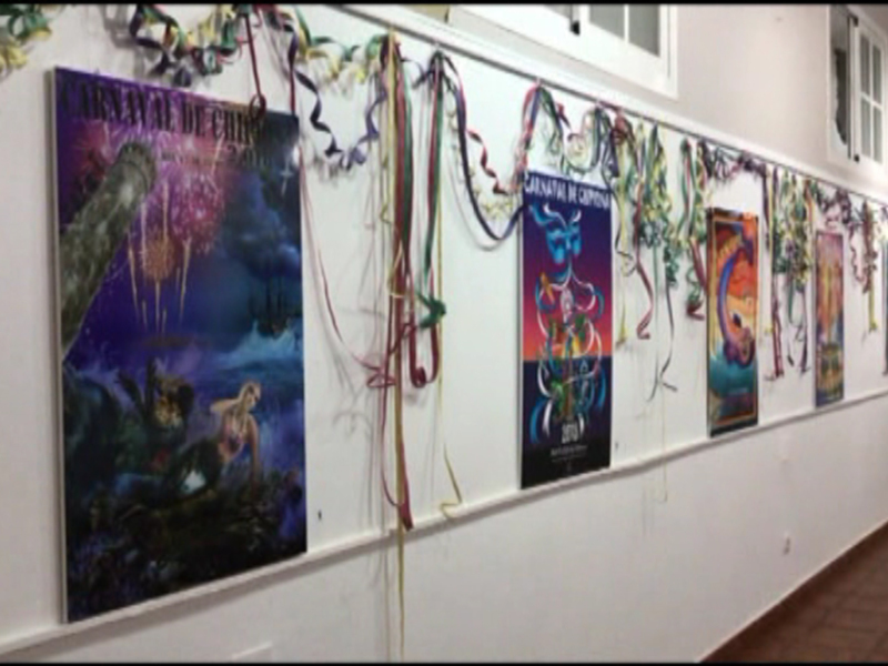 Una pared con varias pinturas y carteles de carnaval, decorados con serpentinas y serpentinas coloridas.