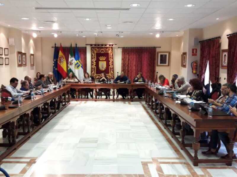 Sala de reuniones con mesas largas, sillas, banderas y carteles.