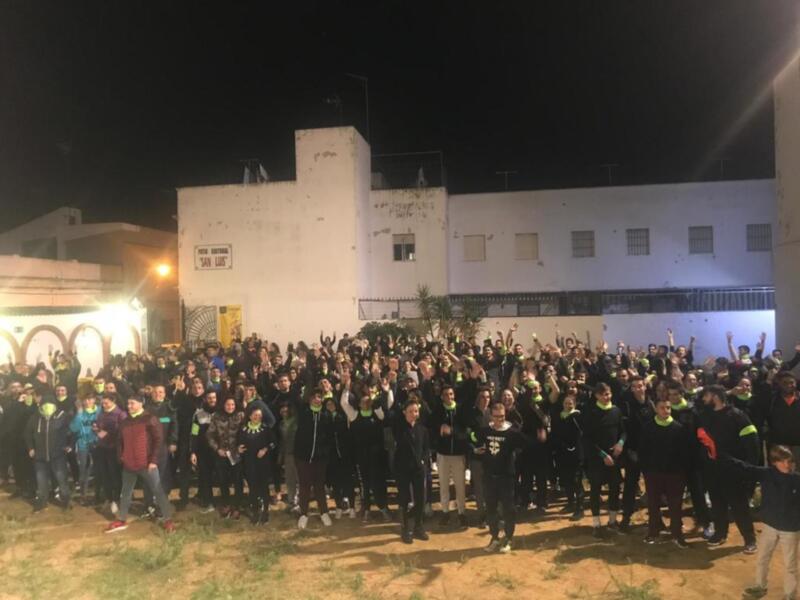 Grupo de personas celebrando en la noche frente a un edificio iluminado.