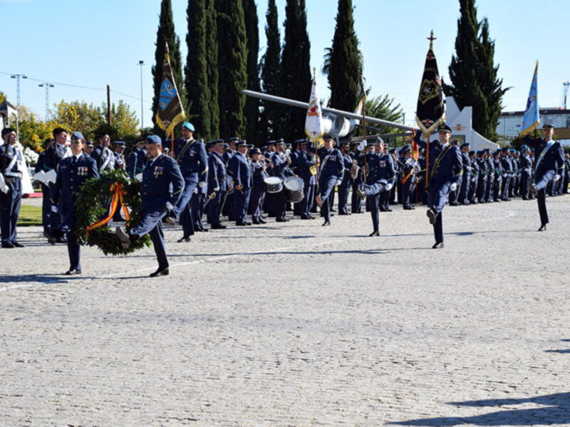 Desfile militar con uniformes y banderas en una plaza al aire libre.